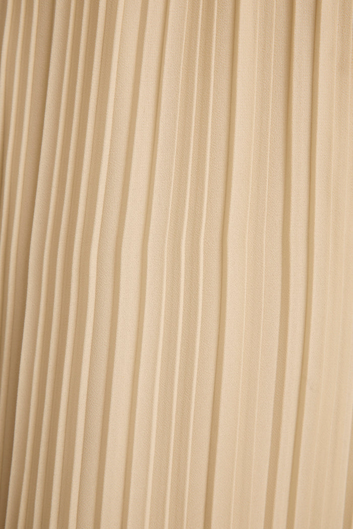 Close-up of cream plisse pleated fabric texture on the Costa halter top.