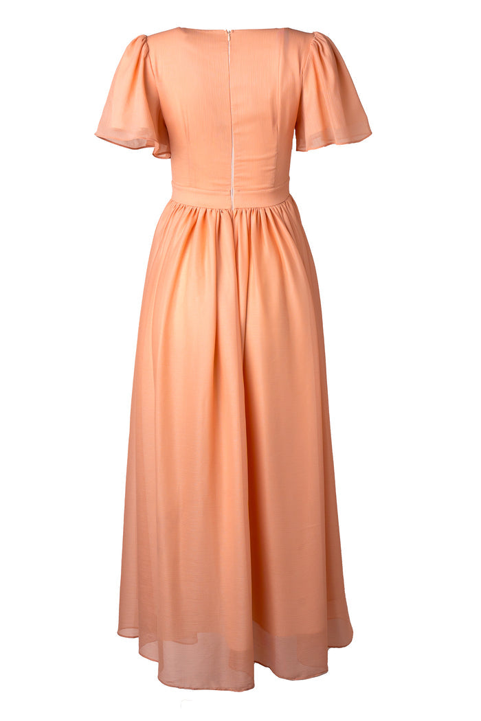 The Abbie Dress in Apricot Crush by Ivy City Co is a peach-hued, short-sleeve maxi with puff sleeves, fitted bodice, gathered waist, and back zipper. Its light, flowy fabric offers an elegant look—ideal as a bridesmaid dress.