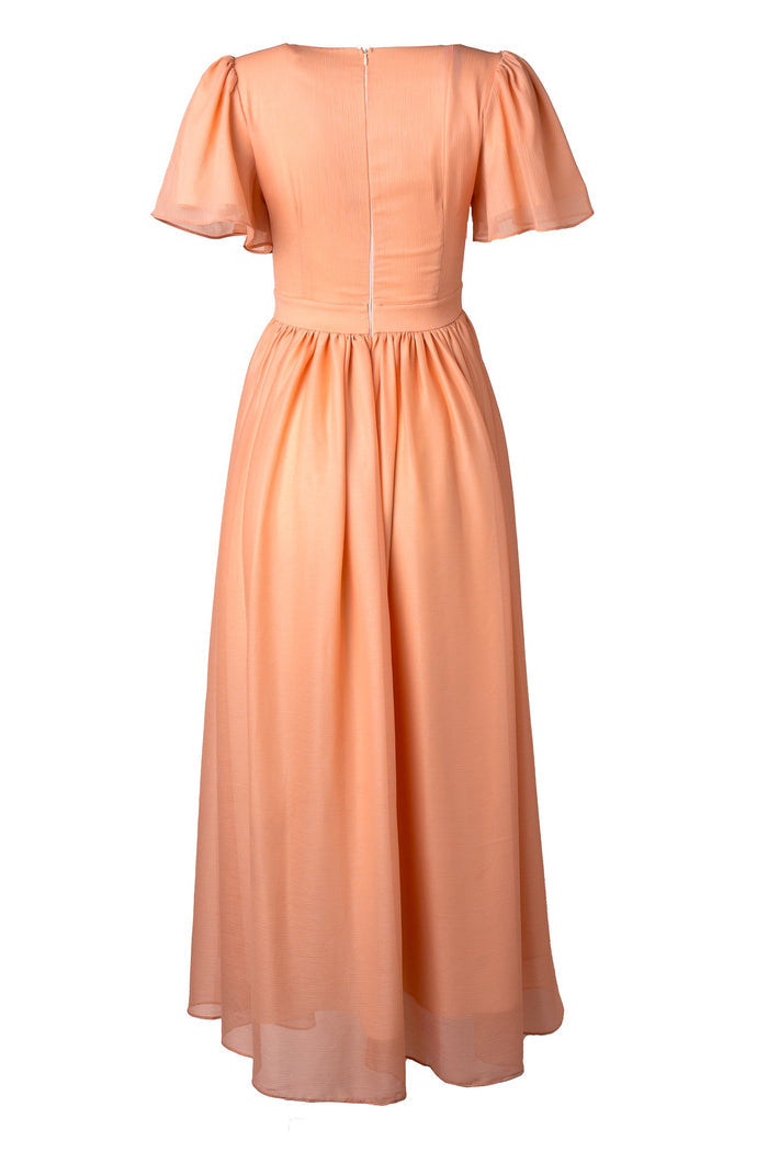 Abbie Dress in Apricot Crush by Ivy City Co: Peach-colored, short-sleeve, ankle-length dress featuring a fitted bodice, flared skirt, and visible back zipper, displayed on a white background. This versatile maxi dress is an elegant choice for bridesmaids or any special occasion.