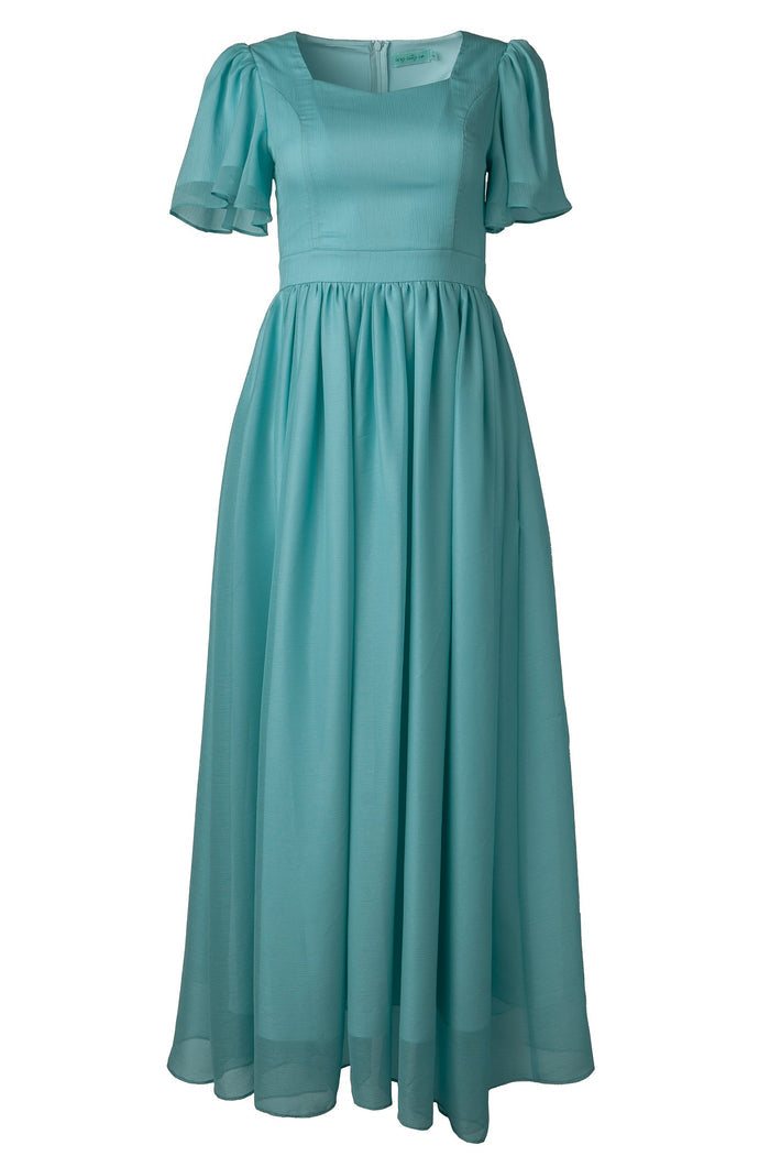 The Abbie Dress in Seaglass Chiffon by Ivy City Co is a long, light blue dress featuring short puffed sleeves, a fitted bodice, and a flowing gathered skirt. With its square neckline and airy Seaglass Chiffon fabric, this elegant design is ideal for bridesmaids or formal and semi-formal occasions.