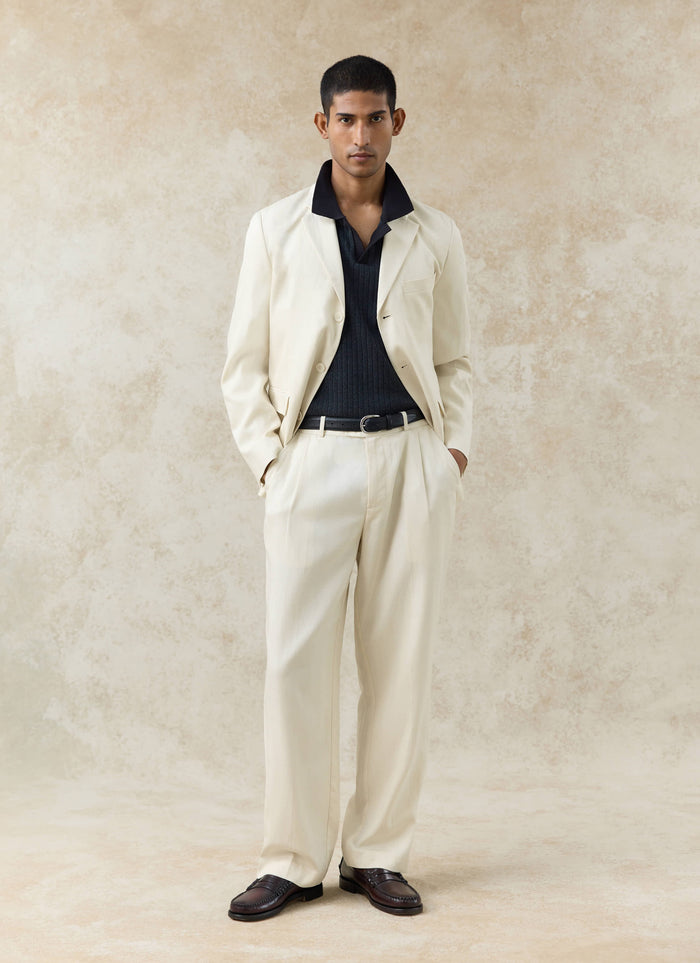 Model wearing the black Percival Anthony Ribbed Polo under a cream suit, showing the textured knit and open collar.