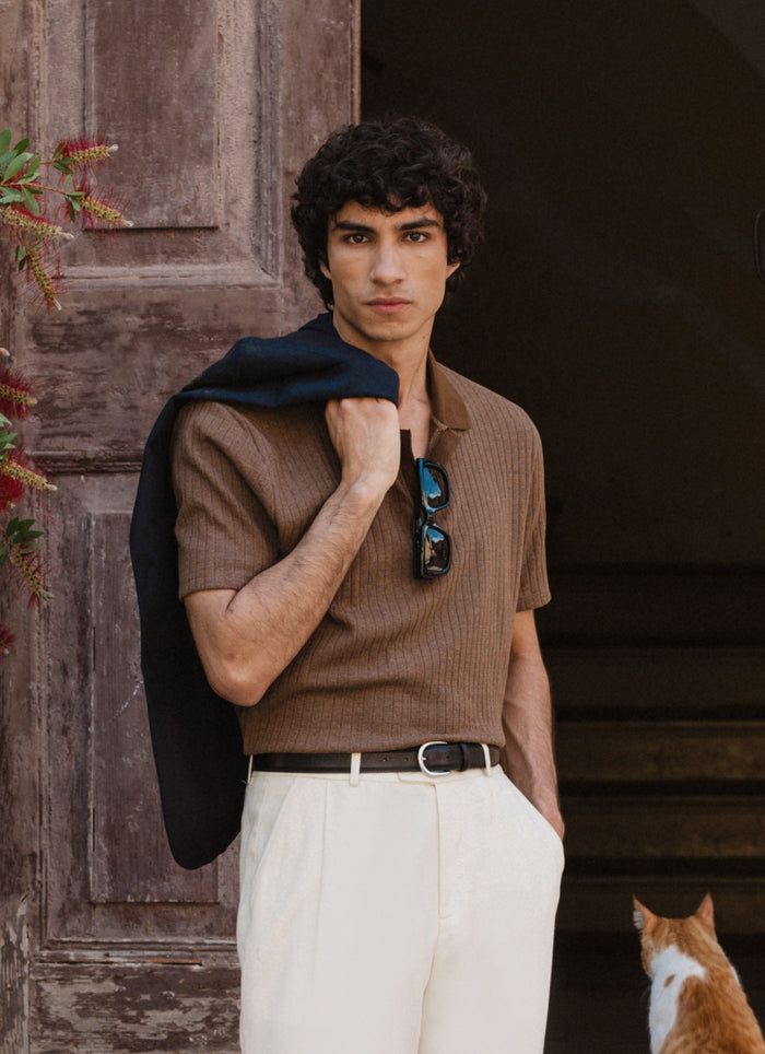 Model wears the espresso brown Percival Anthony Ribbed Polo, a textured cotton knit styled with cream trousers.