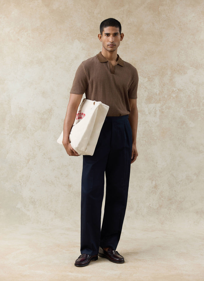 Percival Anthony ribbed polo in espresso, navy cotton Blake double pleated trousers and cream Gordon tote bag on a model.