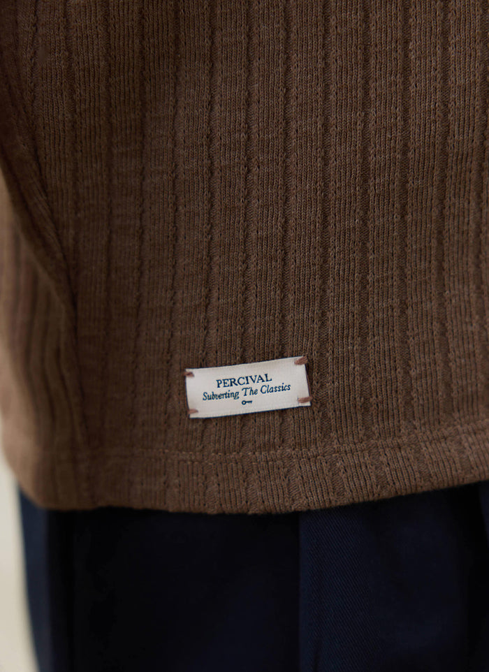 Close-up of the espresso brown ribbed knit fabric on the Percival Anthony Polo, featuring the white brand hem tag.