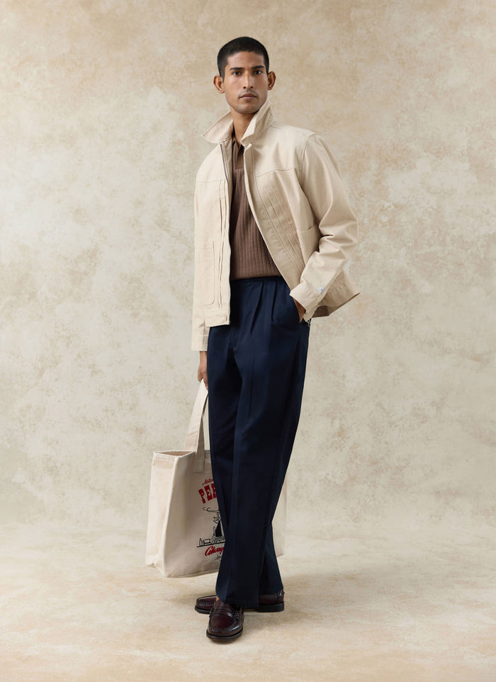 Percival navy cotton Blake double pleated trousers styled with an espresso Anthony ribbed polo and cream zip-up jacket.