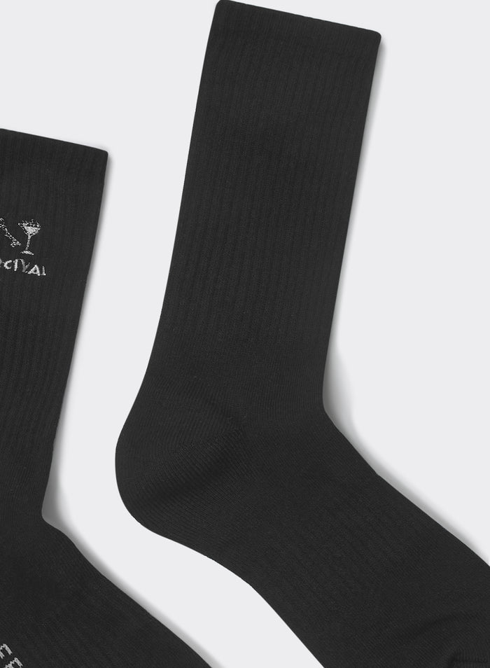 Black Percival Aperitivo socks in ribbed cotton-blend with white cocktail glass embroidery, flat against grey background.