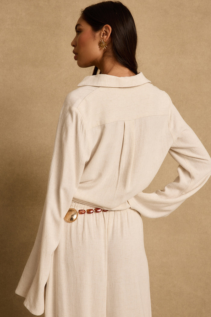 Back view of natural linen collared blouse with bell sleeves, styled with matching skirt.