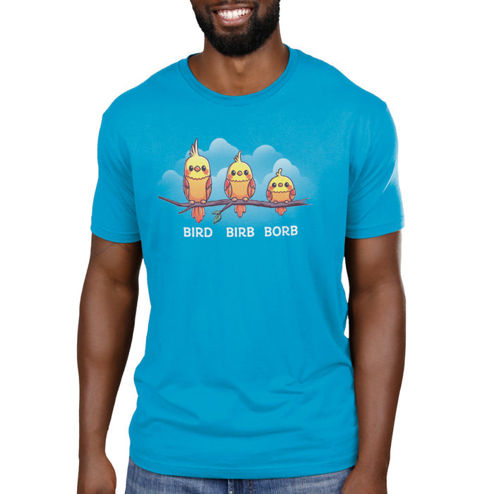 Premium Cotton T-shirt_Teeturtle Bird. Birb. Borb. cobalt blue t-shirt featuring three cartoon birds with varying levels of fluffiness sit on a branch against a blue background with clouds. The birds are labeled "Bird," "Birb," and "Borb" from left to right, adding a playful twist to their names, showcasing the Bird.