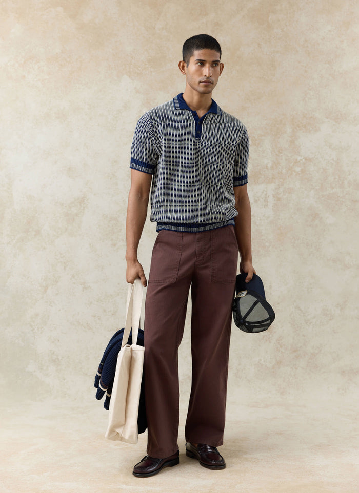 Percival navy Claude knitted polo in two-tone textured cotton, styled with brown trousers and dark loafers.