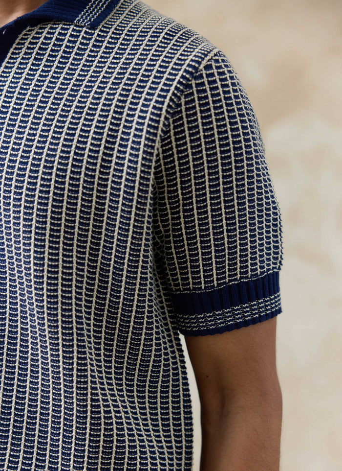 Close-up of the navy Percival Claude Knitted Polo, highlighting the textured two-tone cotton knit and ribbed sleeve cuff.