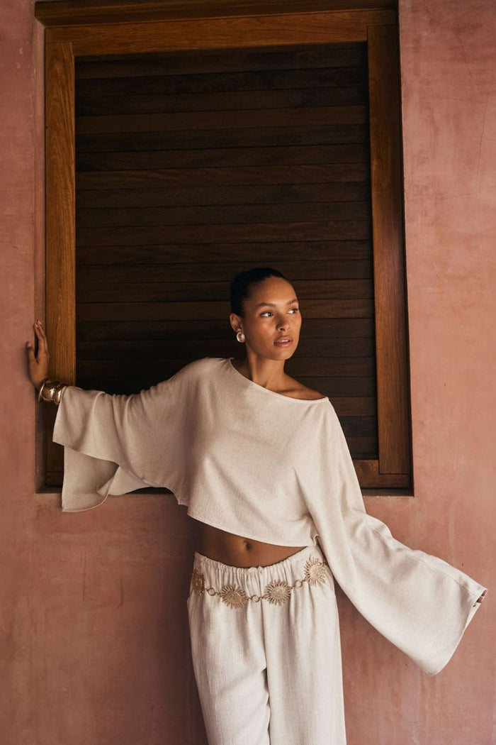 Cropped white linen top with wide bell sleeves worn as matching resort wear set.