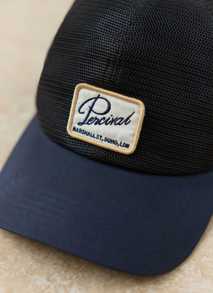 Navy Damien Mesh Trucker Cap by Percival, featuring a breathable mesh crown and an embroidered logo front patch.