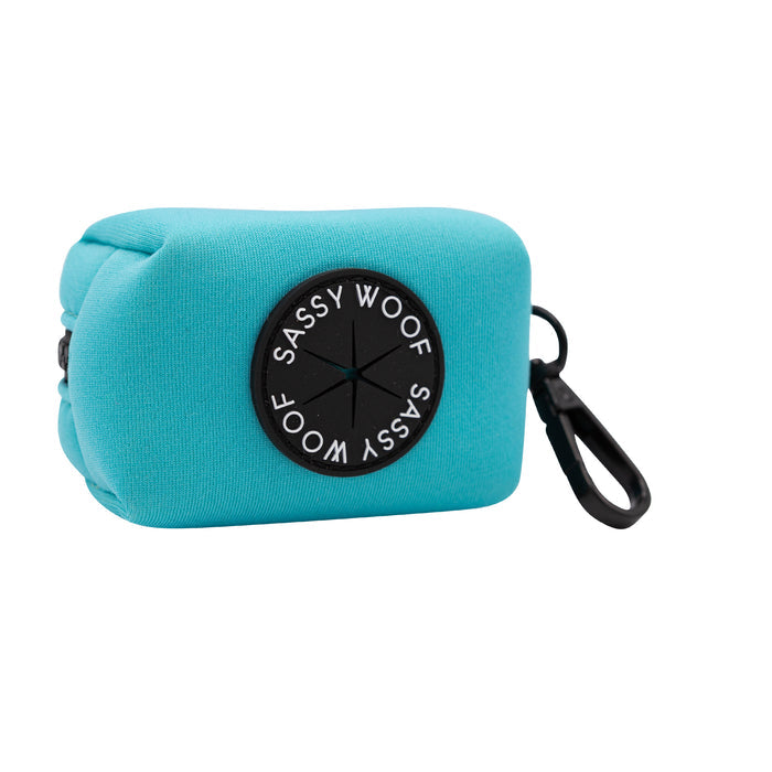 Turquoise rectangular pouch with a black clip and a circular black Sassy Woof label, made of soft fabric. This pouch is perfect for storing small essentials and pairs seamlessly with the Sassy Woof Dog Collar Three Piece Bundle in Neon Blue.