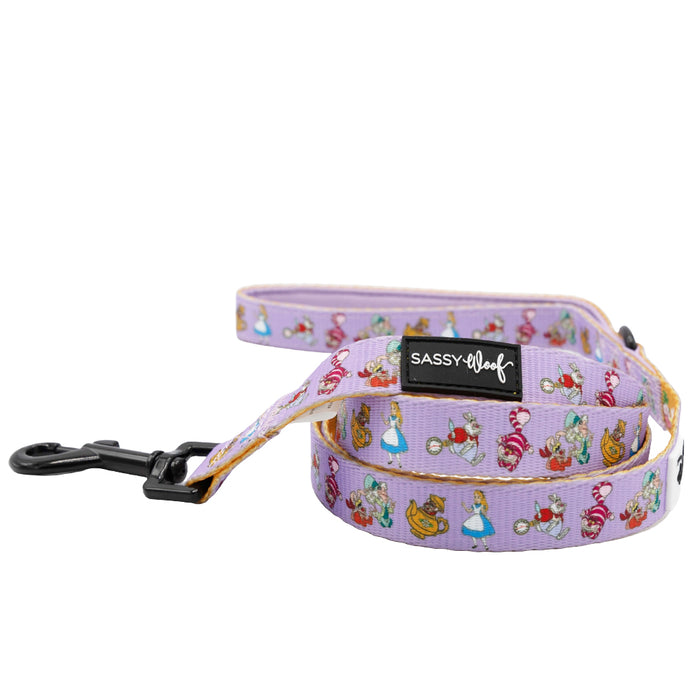 The Sassy Woof Dog Leash - Alice in Wonderland (Purple) features playful characters, a pastel purple design, padded neoprene handle, sturdy black clasp, and branded label—part of the vibrant Sassy Woof collection.