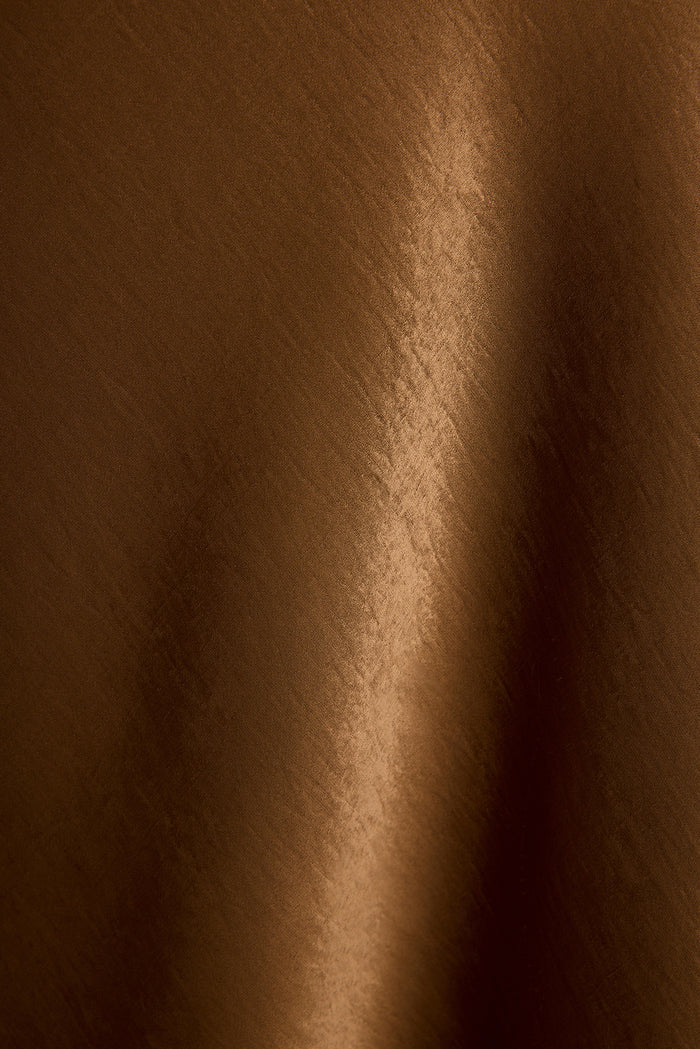 Glossy bronze satin fabric of the Dolce maxi dress in a close-up texture detail.