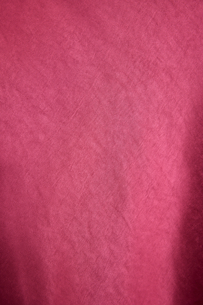 Close-up of fuchsia satin fabric, showing the soft sheen of the Dolce maxi dress.