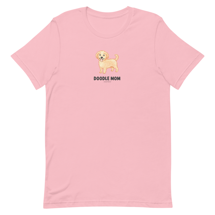 The Sassy Woof Doodle Mom Tee is a light pink unisex shirt with a smiling doodle dog graphic and bold “DOODLE MOM” text—perfect for any proud Doodle Mom.