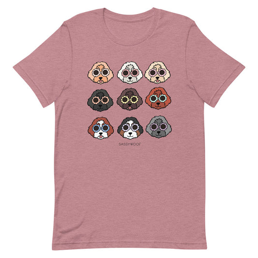 The Sassy Woof Doodle Tee is a mauve unisex t-shirt with nine cartoon dog faces in a grid and “SASSY WOOF” printed underneath. Made from 100% cotton for comfort.