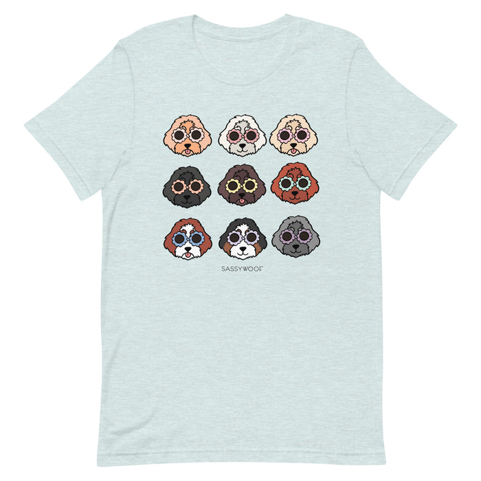 The Doodle Tee by Sassy Woof is a light gray unisex shirt made from 100% cotton, featuring a playful 3x3 grid of cartoon dog faces with round glasses and "SASSYWOOF" printed below the design.
