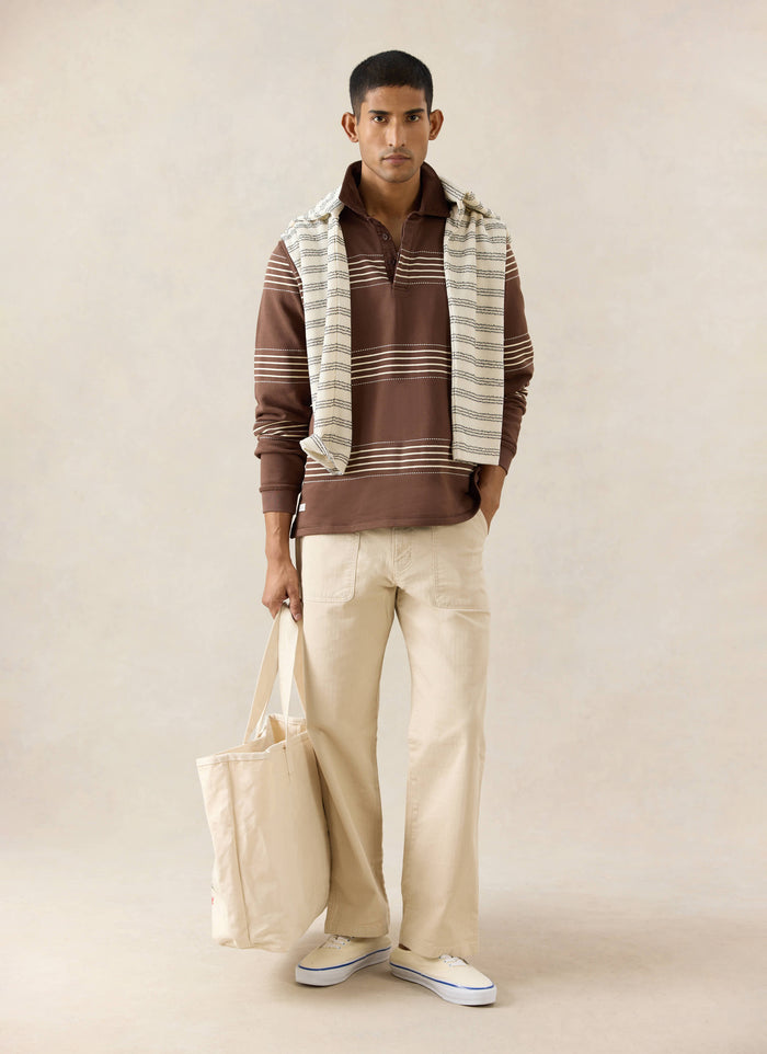 The Percival Editor Striped Rugby Polo in espresso with stab stitching, styled with cream Lucas carpenter trousers.