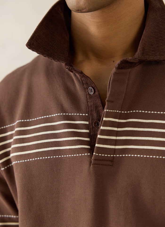 Percival Editor Rugby Polo in espresso brown, featuring a cord collar, white stab stitching, and striped cotton fabric.