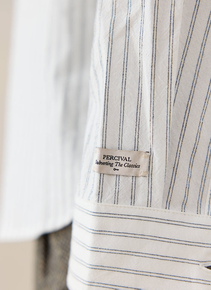 Close-up of the white cotton Fabian Striped Shirt by Percival, featuring the branded label and thin blue vertical stripes.
