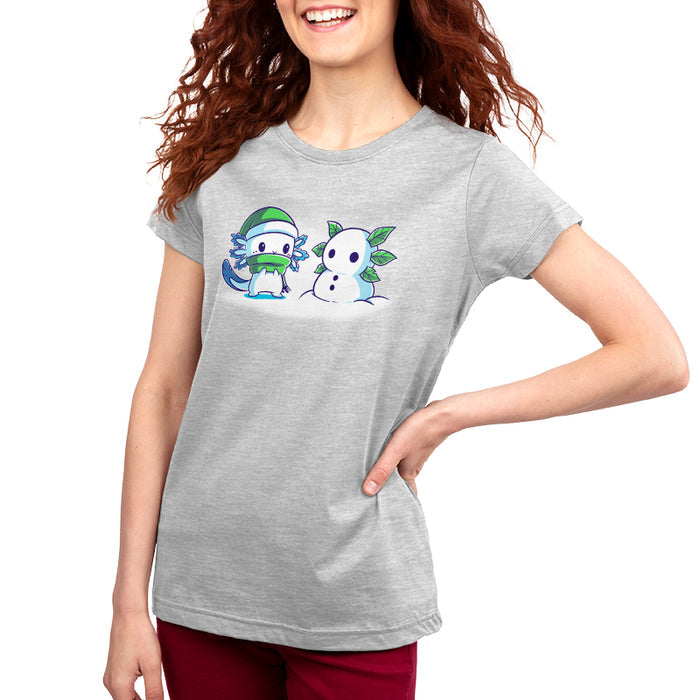 Premium Cotton T-shirt_TeeTurtle Frosty Friend A cute, blue cartoon creature with a green hat and scarf stands next to its Frosty Friend, a snowman with leaf arms, in a snowy setting.