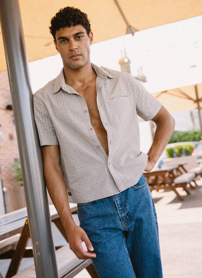 Percival Hinsley boxy cream check 100% cotton short sleeve shirt, paired with mid-wash blue heritage denim jeans.