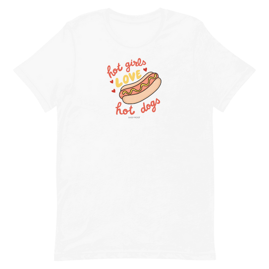 The Sassy Woof Hot Girls Love Hot Dogs Tee is a white unisex t-shirt with a fun hot dog graphic and playful “hot girls love hot dogs” text in red and orange, printed using eco-friendly ink.