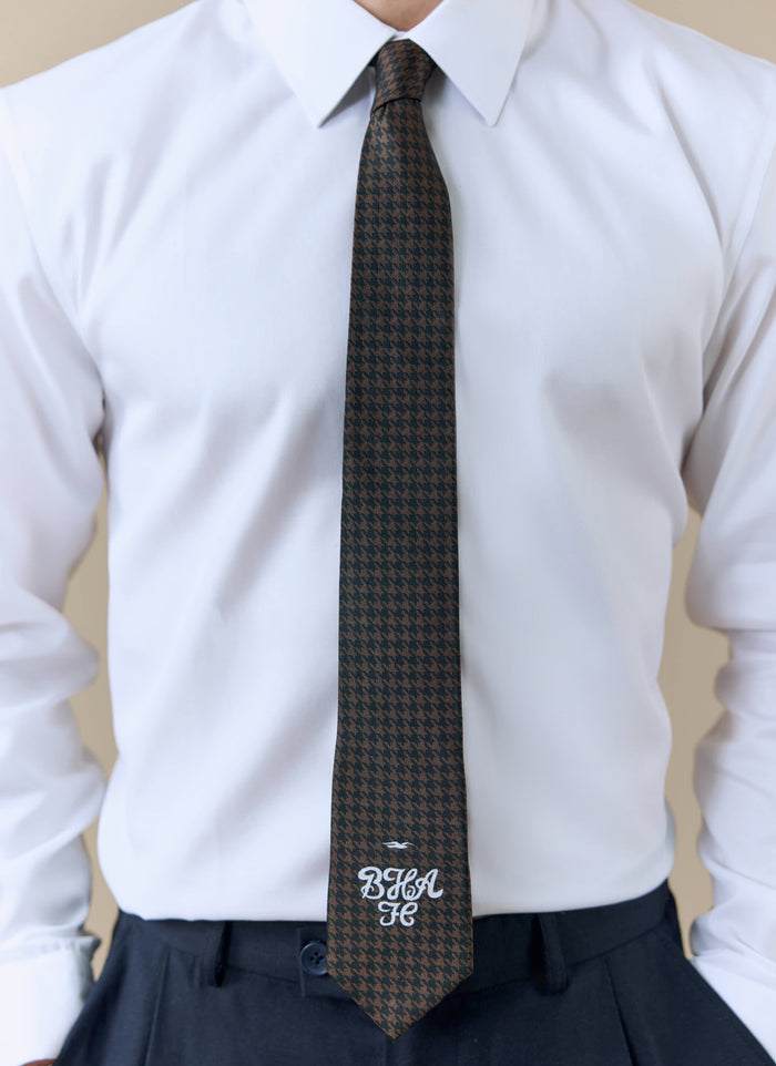 A model wearing the Percival x Brighton & Hove Albion F.C. brown houndstooth silk tie with a crisp white shirt.