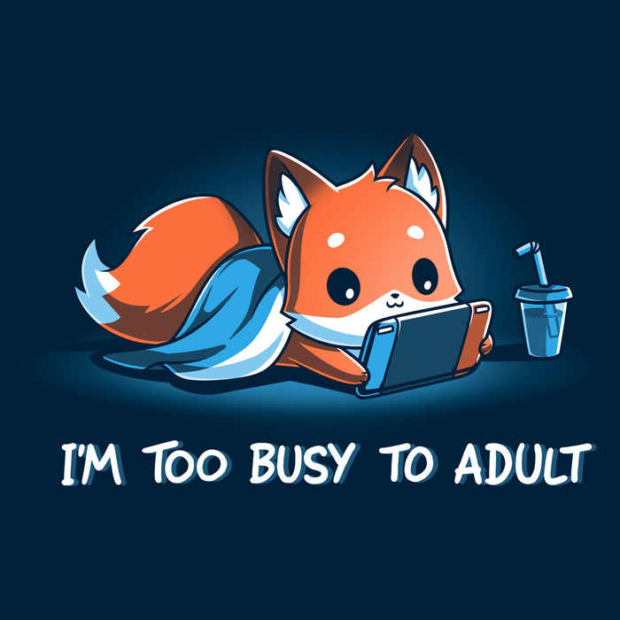 Classic Cotton T-shirt_TeeTurtle I'm Too Busy to Adult navy blue t-shirt featuring a fox lying down with a blue blanket, holding a video game tablet, next to a drink with a straw. Text below reads, "I'M TOO BUSY TO ADULT."
