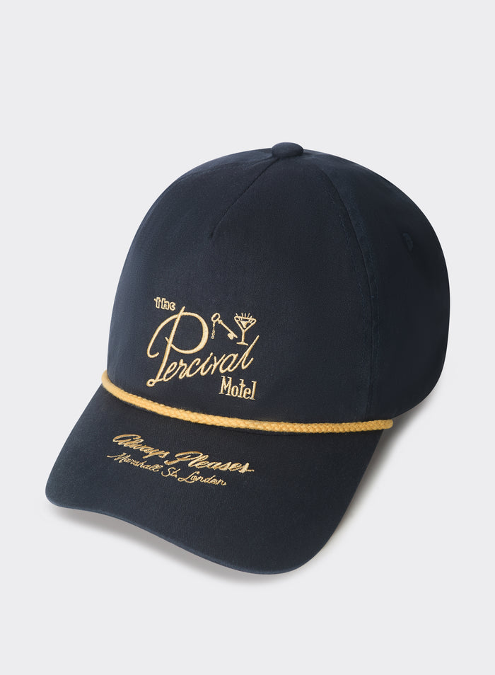 The Percival Kingsley trucker cap in navy cotton with gold motel embroidery and braided rope, shot on a grey background.