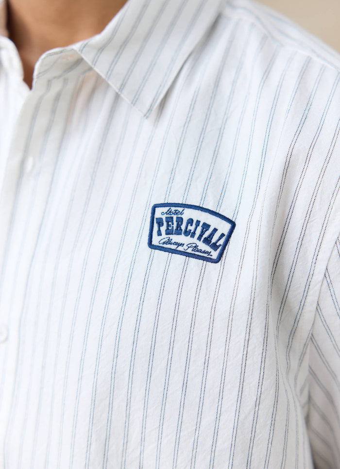 Close-up of the blue embroidered motel badge on the Percival Lucia cream stripe shirt in breathable cotton.