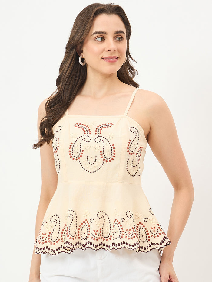 Woman wearing a beige top with floral patterns on a white background