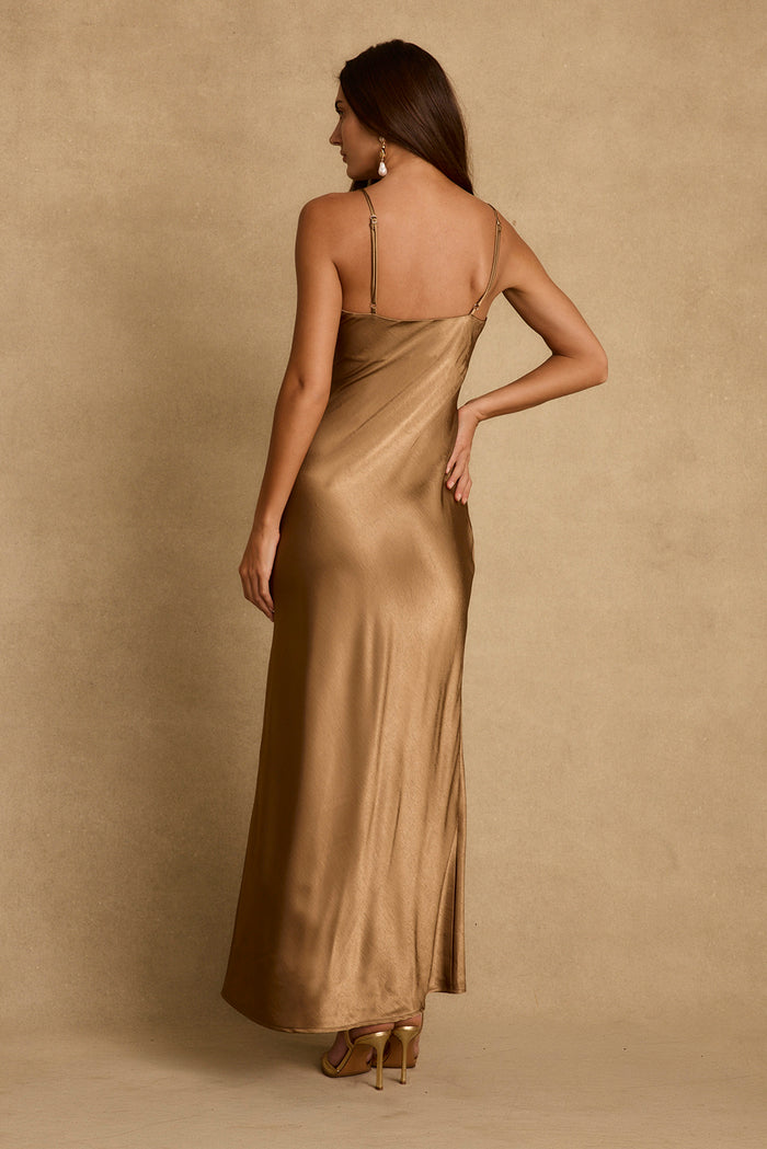 Back view of the bronze satin maxi slip dress with adjustable straps and gold heels.