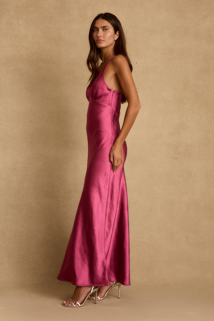 Side profile of the Mirabella fuchsia satin maxi dress styled with metallic strappy heels.