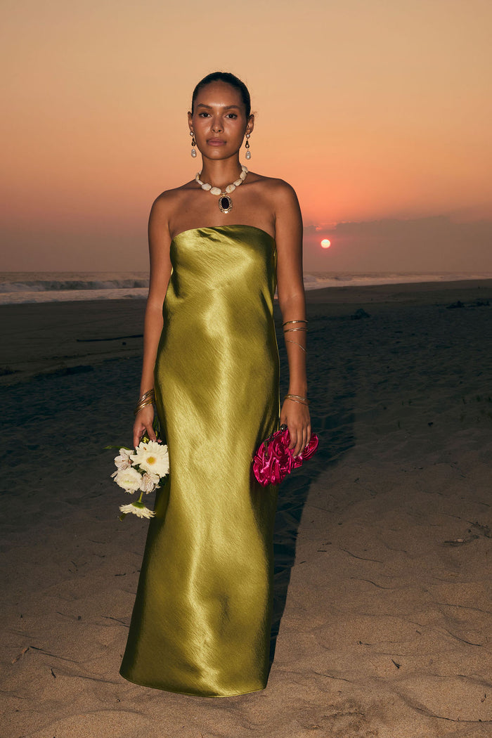 Model wearing the 12th Tribe Natalia Chartreuse Strapless Maxi Dress in a light green satin. Featuring a strapless neckline and elegant maxi silhouette. Style with strappy heels for bachelorette parties, weddings, and vacation dinners.