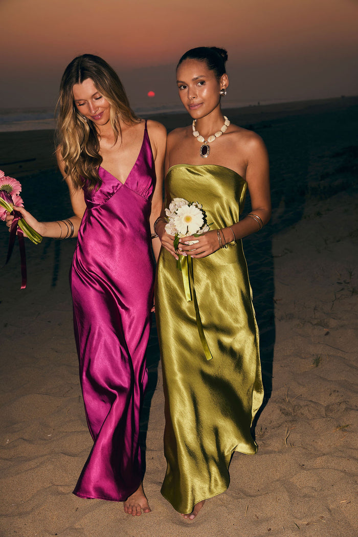 Chartreuse satin strapless maxi dress worn on a beach at sunset, holding daisies.