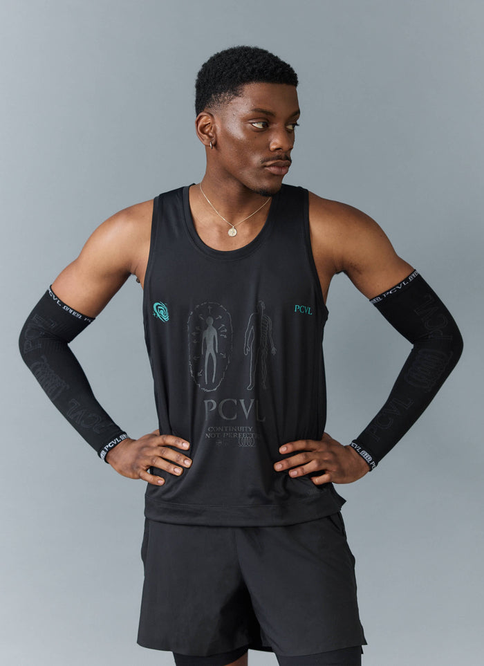 A model wears the Percival PCVL Arm Compression sleeves in black with an athletic vest, posing with hands on hips.