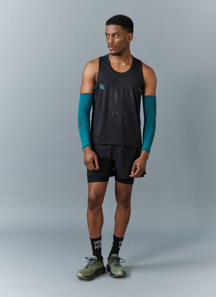 A model wears an athletic outfit from Percival, including a black technical vest and blue arm compression sleeves.