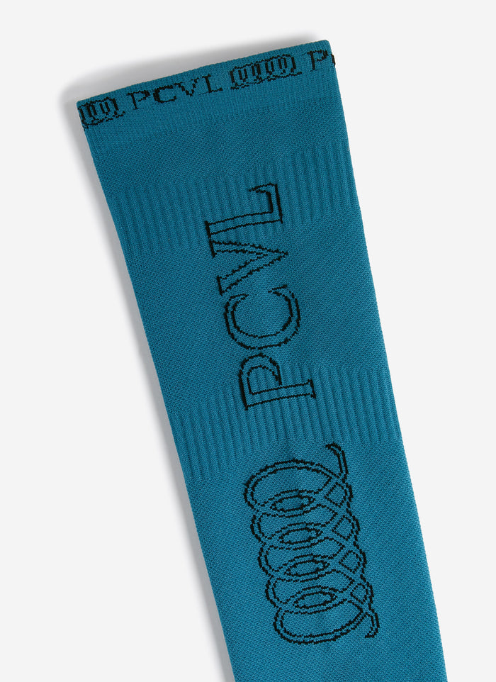 A close-up of the blue PCVL Arm Compression sleeve from Percival, showing the black jacquard branding and logo detail.