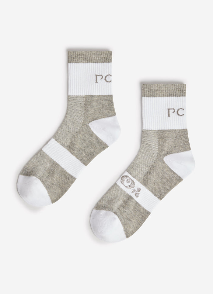 The Percival PCVL Performance Socks in white and grey, laid flat to show the PC branding on the ribbed cuff.