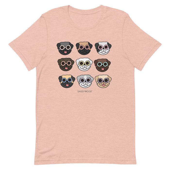 The Pug Tee by Sassy Woof is a light pink unisex t-shirt featuring nine illustrated pug faces in sunglasses and "SASSYWOOF" printed below—an ideal dog lover shirt for any collection.