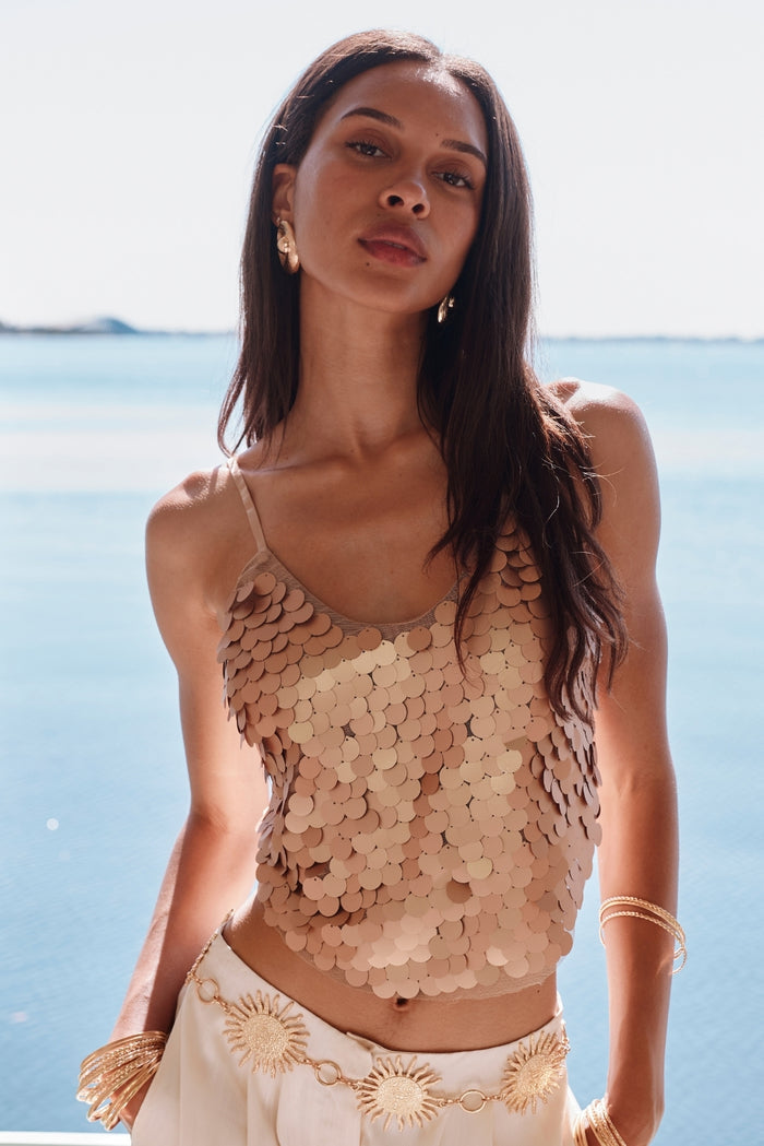 Rose gold paillette tank styled with cream trousers and gold sun belt by the sea.