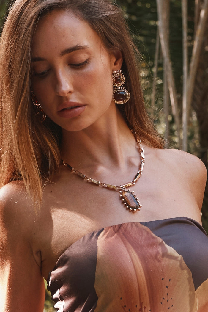 Amber stone drop earrings and matching pendant necklace styled with a floral strapless resort dress.