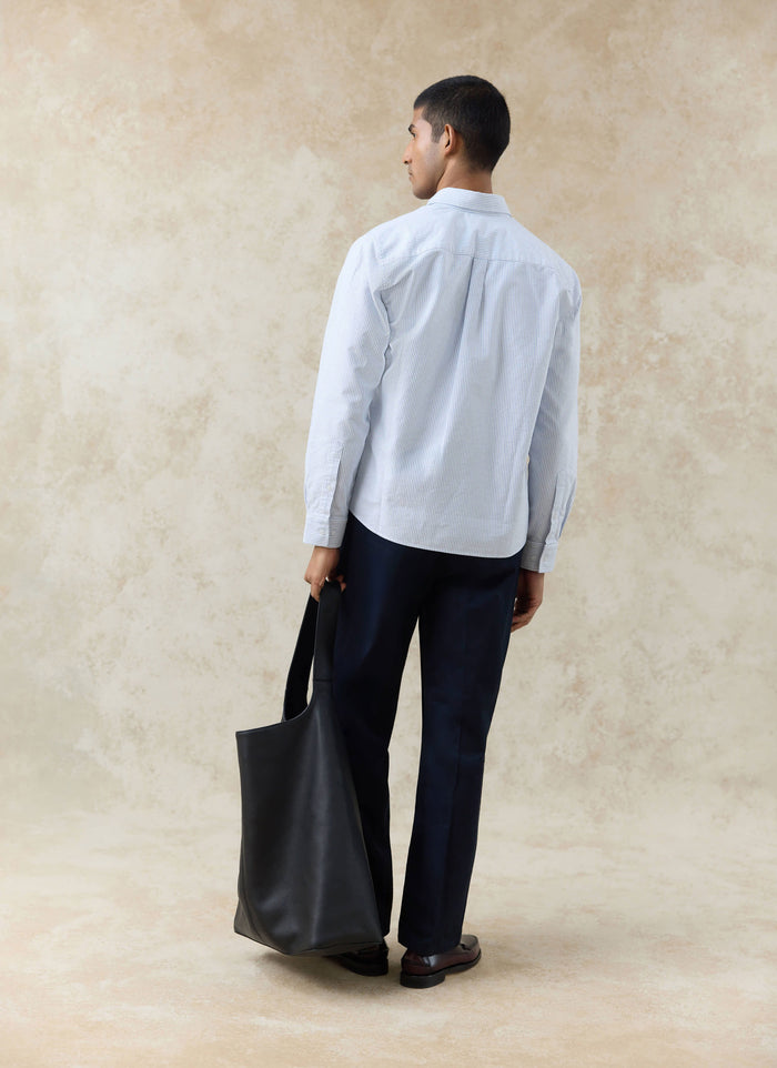 Rear view of a model in the Percival blue striped Oxford shirt and navy cotton Blake double pleated trousers.