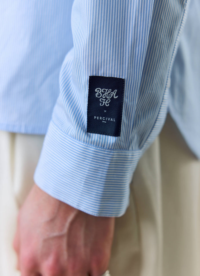 A close-up of the Percival x Brighton & Hove Albion F.C. woven label on the sleeve of the striped Pearce shirt.