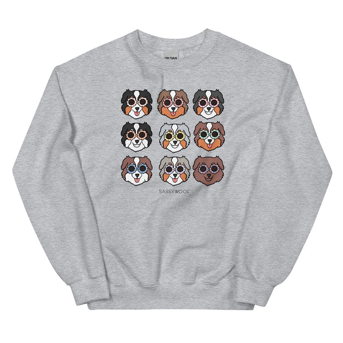 The Sassy Woof Sweatshirt - Aussies features nine cartoon Australian Shepherd faces with unique coats above the Sassy Woof logo—this cozy unisex sweatshirt is perfect for dog lovers.