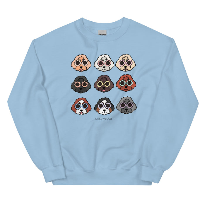 The Sassy Woof Sweatshirt - Doodles is a light blue unisex crewneck with a 3x3 grid of colorful cartoon dog faces and "SASSY WOOF" text—perfect for dog lovers wanting playful style.