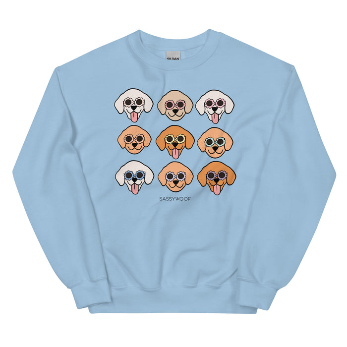 The Sassy Woof "Sweatshirt - Goldens" is a light blue unisex crewneck in a comfy cotton blend, featuring nine cartoon dogs with sunglasses and tongues out. "SASSYWOOF" is printed below the playful dog designs.